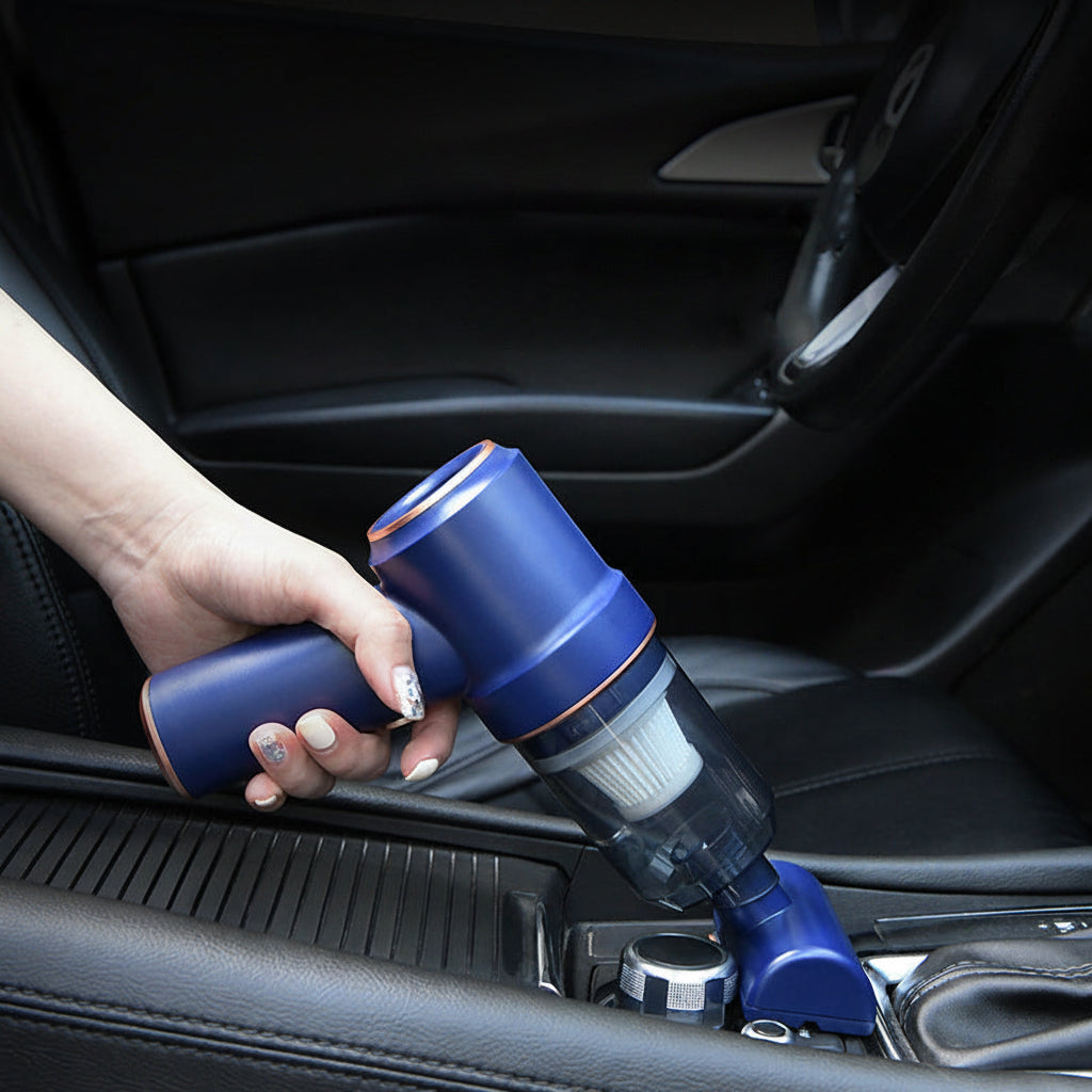 Hand holding a blue handheld vacuum cleaner inside a car.
